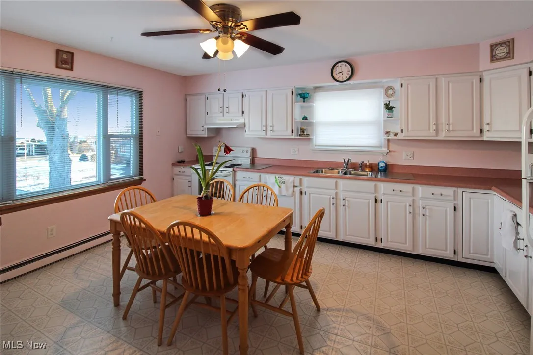 Dining space featuring a baseboard heating unit, sink, and ceiling fan