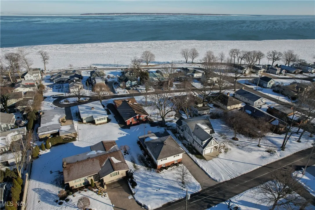 Snowy aerial view featuring a beach view and a water view