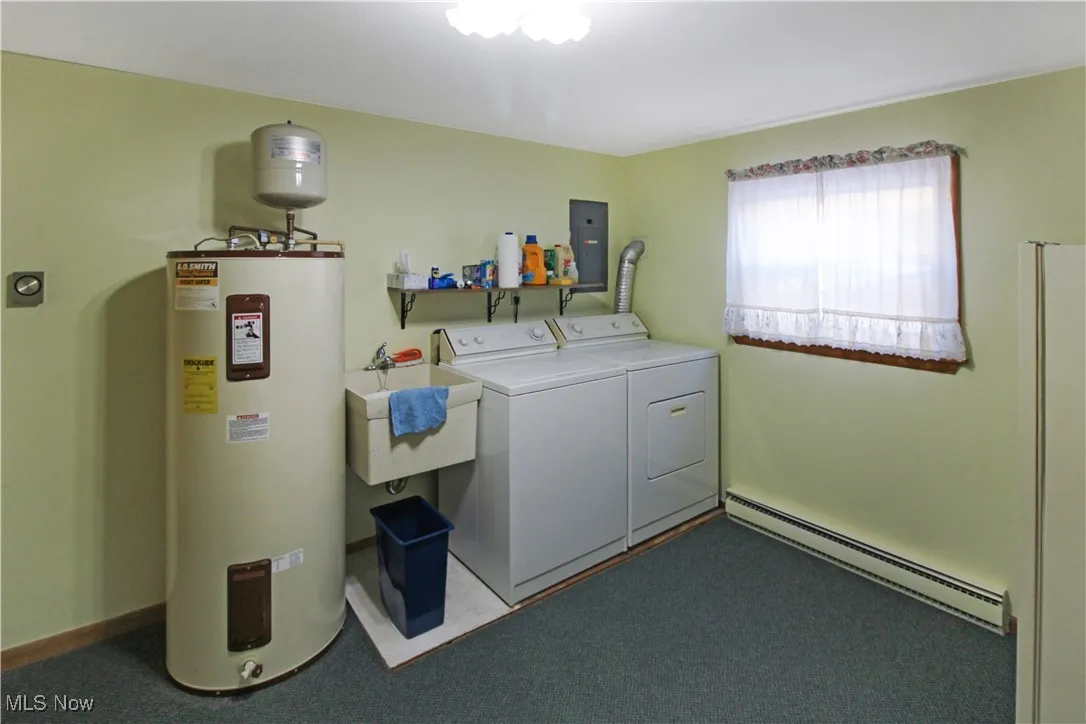 Washroom featuring sink, dark colored carpet, a baseboard radiator, electric water heater, and independent washer and dryer