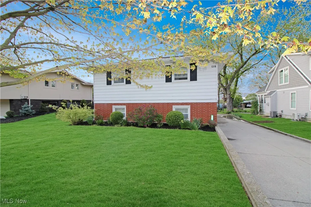 Tri-level home with brick siding, central AC unit, and a front lawn