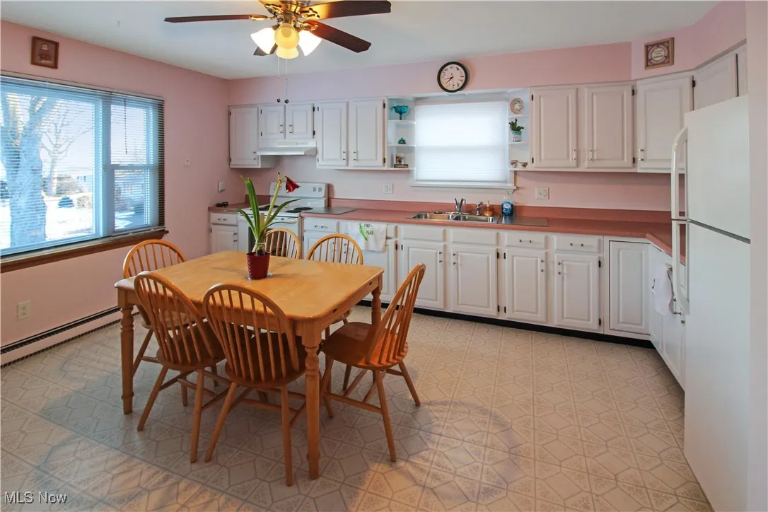 Kitchen with white cabinetry, sink, white appliances, and a baseboard heating unit