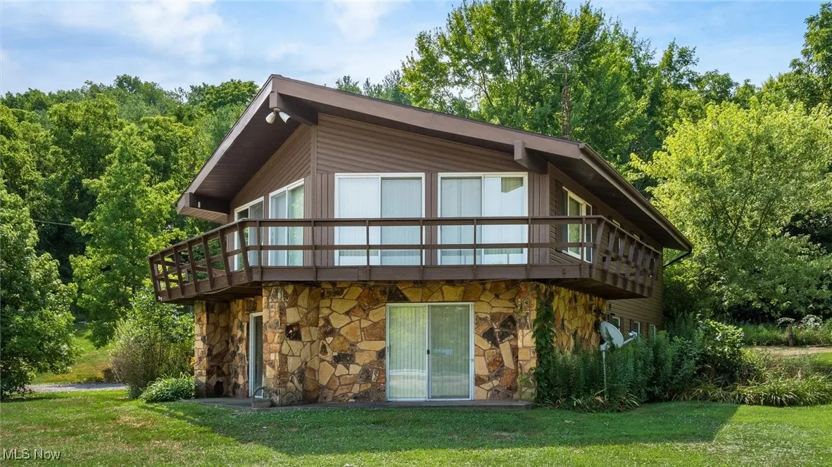 Rear view of property with a wooden deck and a lawn