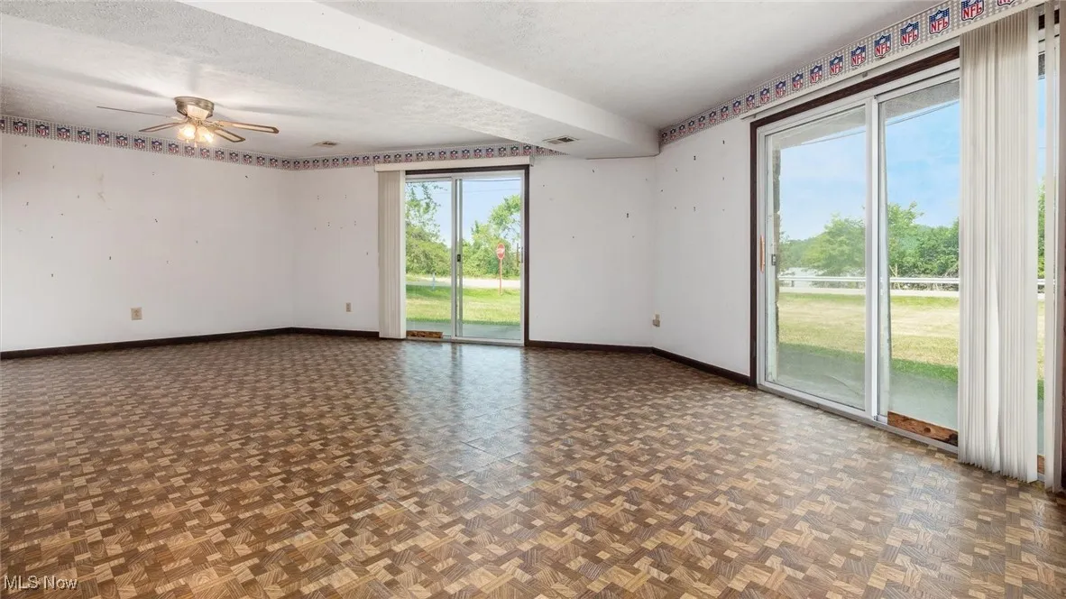 Spare room featuring dark parquet flooring, ceiling fan, and a textured ceiling