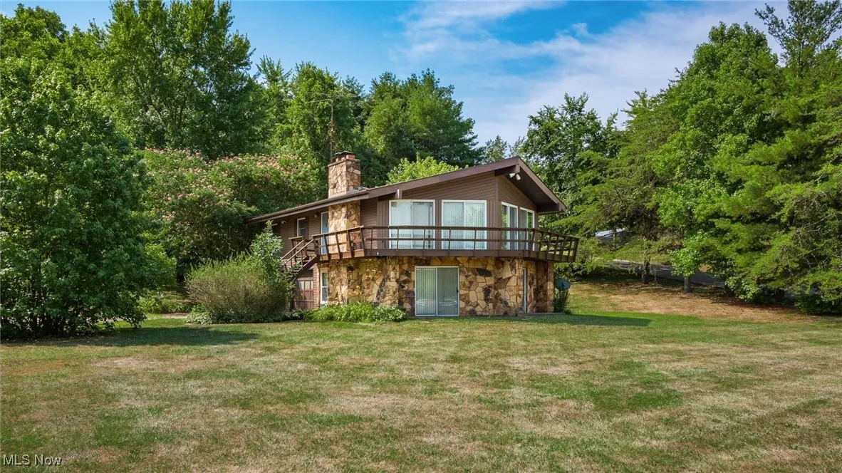 Rear view of property featuring a wooden deck and a yard
