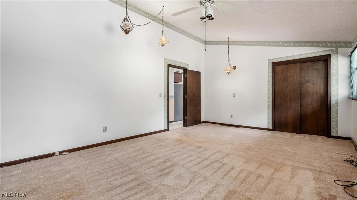 Carpeted spare room with a towering ceiling and ceiling fan