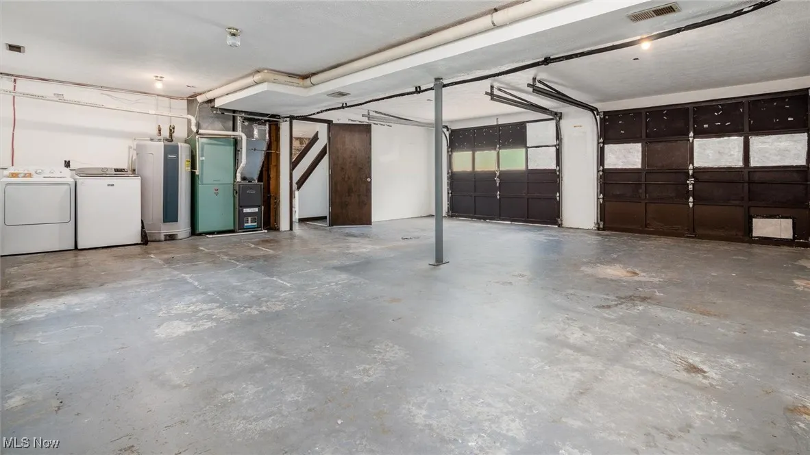 Garage featuring independent washer and dryer, water heater, and heating unit