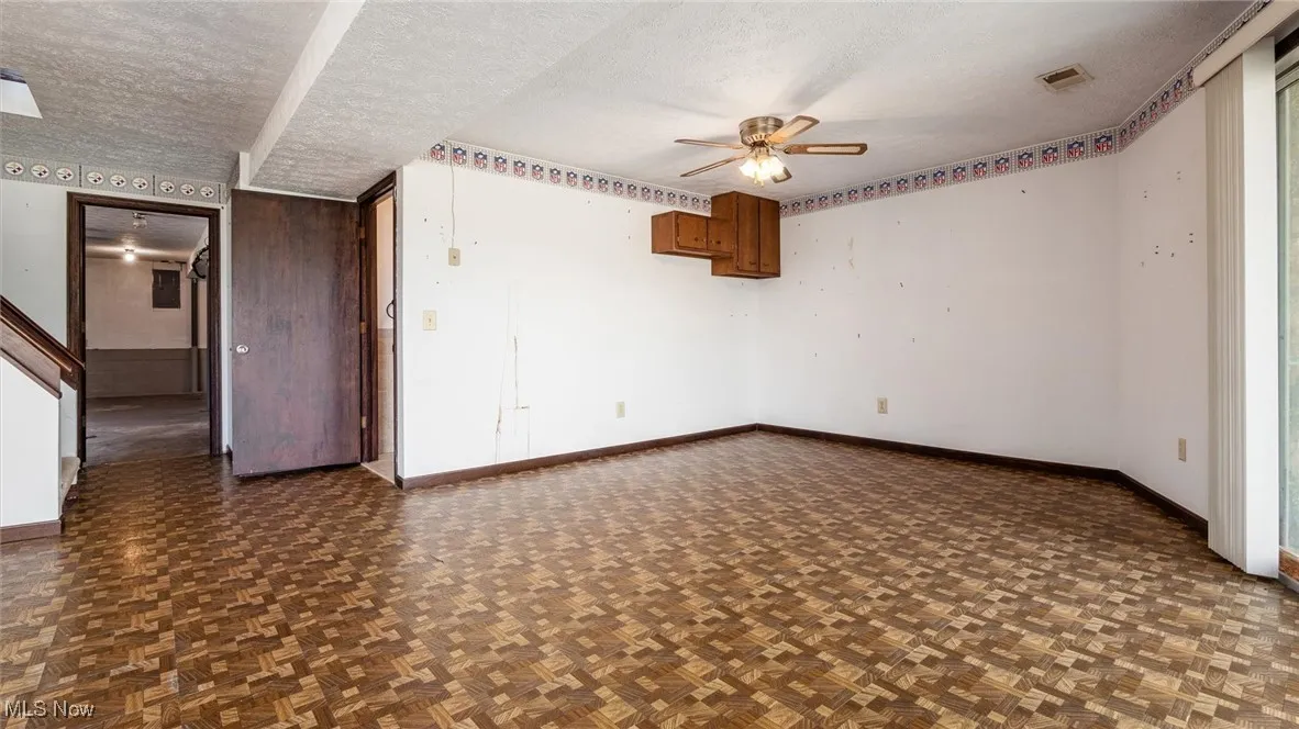 Spare room with ceiling fan, dark parquet flooring, and a textured ceiling