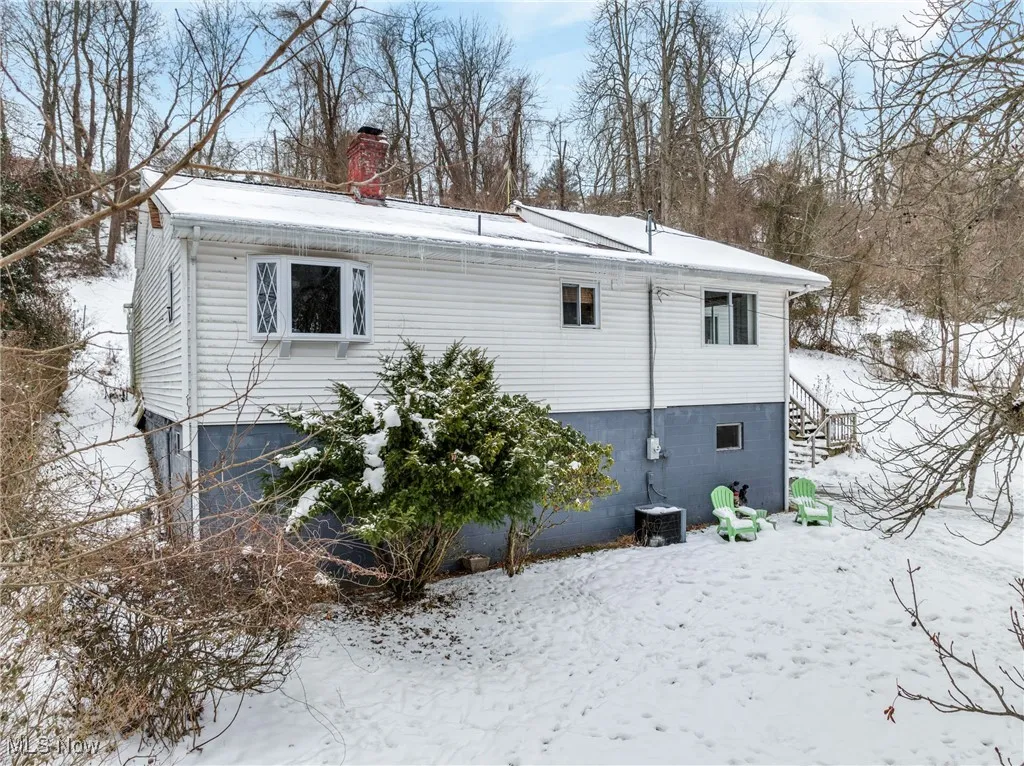 Snow covered back of property featuring cooling unit