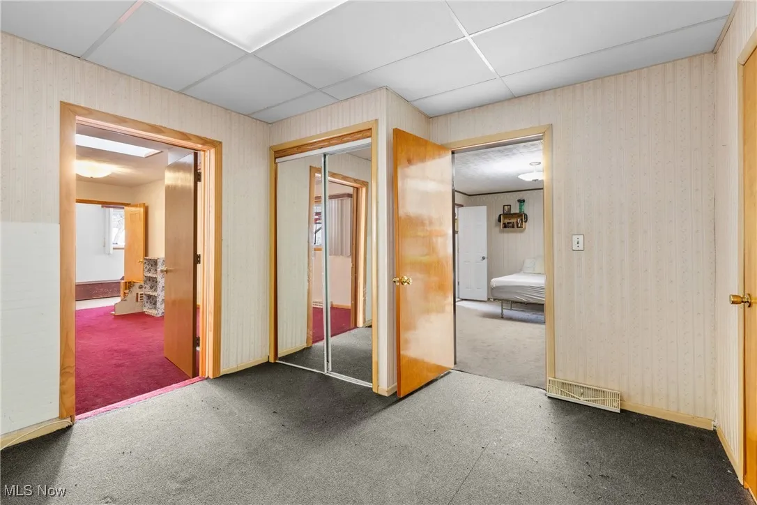 Hallway with a paneled ceiling and carpet floors