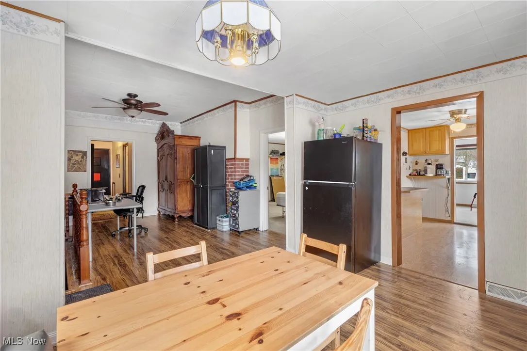 Dining space featuring hardwood / wood-style flooring, ornamental molding, and ceiling fan with notable chandelier
