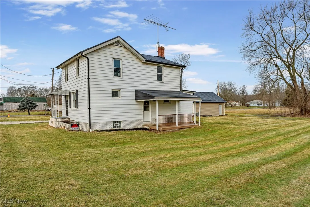 Rear view of house featuring a porch and a lawn