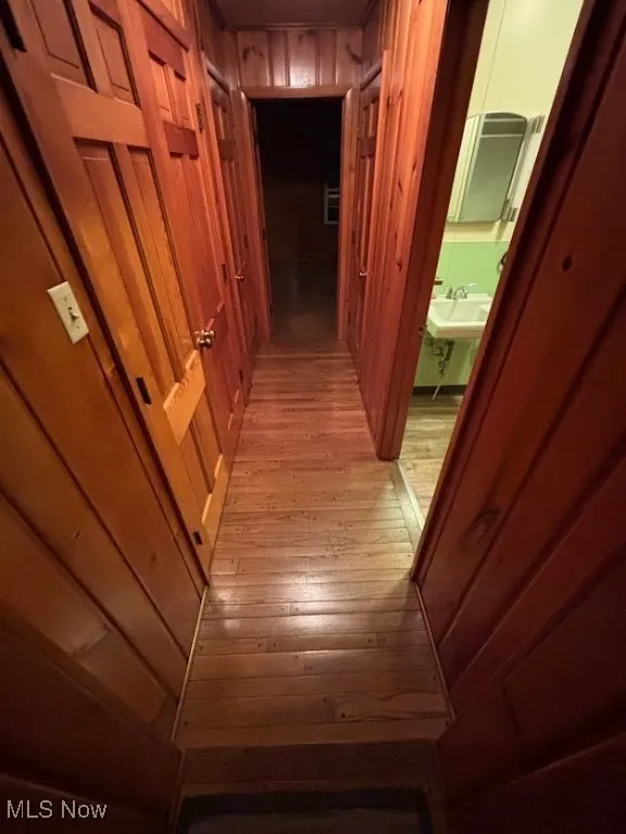 Corridor featuring light wood-type flooring and wood walls