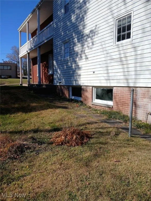 View of side of home featuring a balcony and a lawn