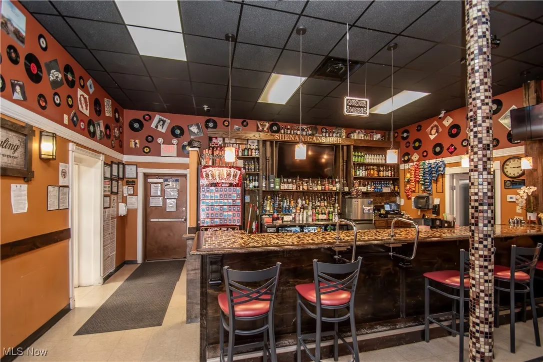 Bar with a paneled ceiling and decorative light fixtures