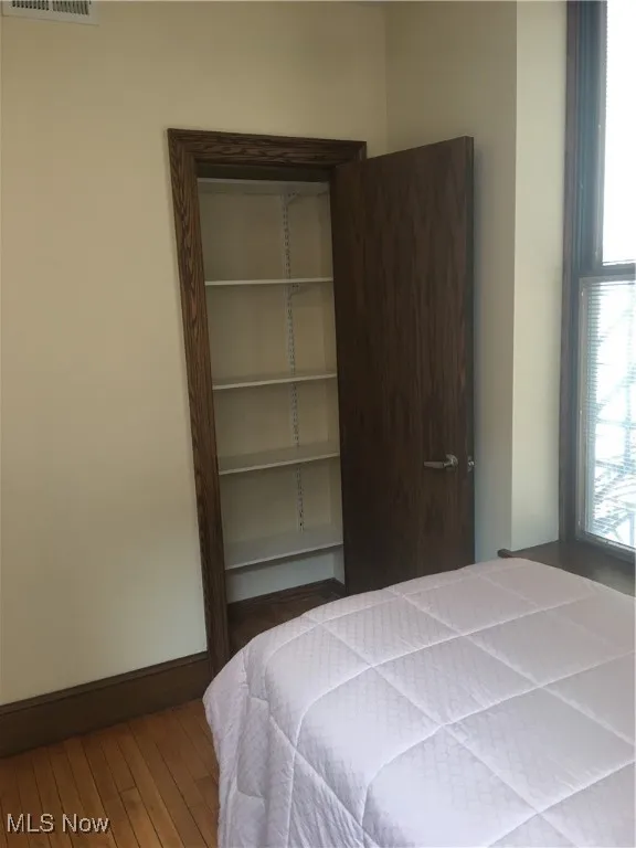 Bedroom with a closet, wood-type flooring, and multiple windows