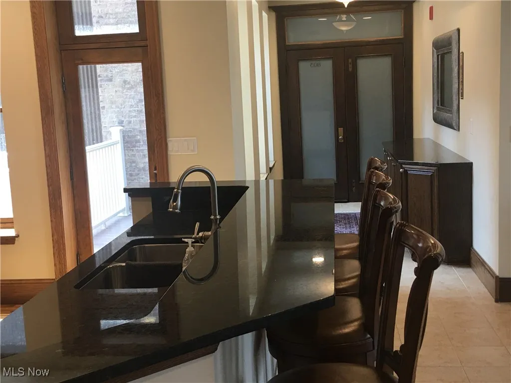 Kitchen featuring french doors, dark stone countertops, sink, and light tile patterned floors
