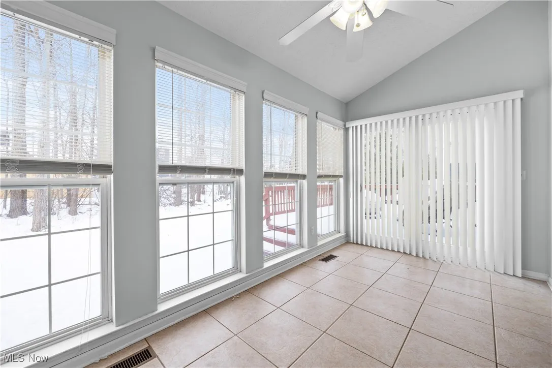 Unfurnished sunroom with ceiling fan and vaulted ceiling
