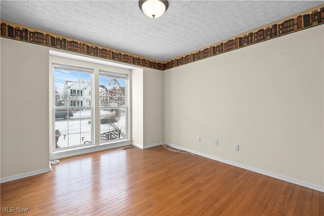 Unfurnished room with hardwood / wood-style floors and a textured ceiling