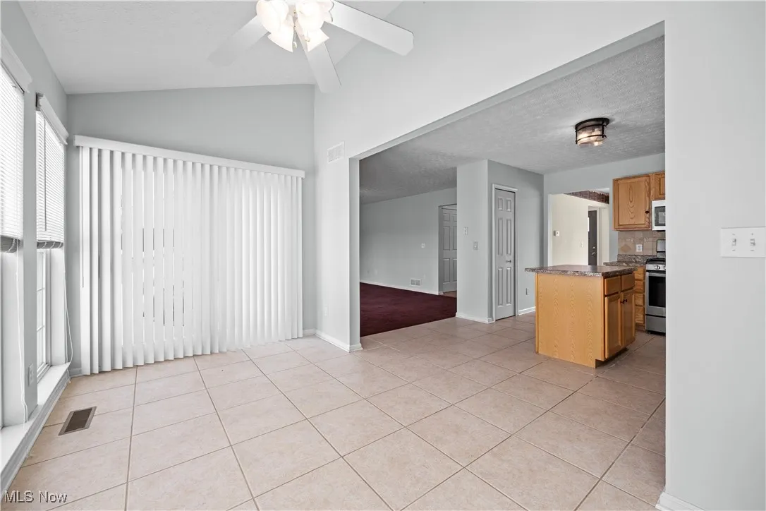 Kitchen with light tile patterned floors, ceiling fan, backsplash, stainless steel appliances, and kitchen peninsula