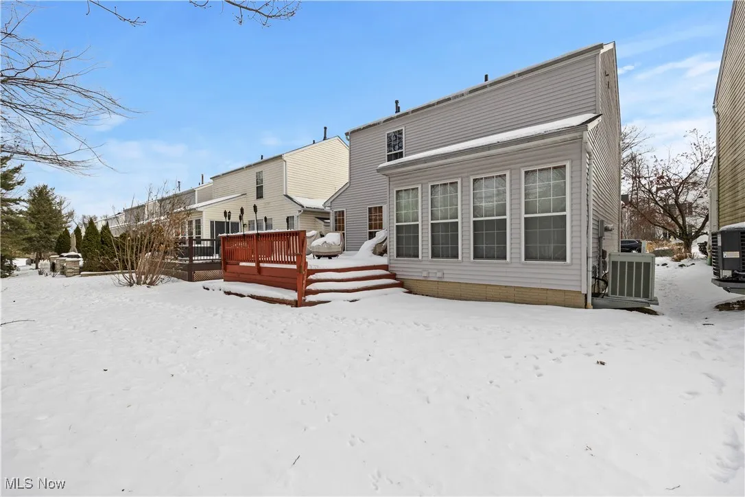 Snow covered property featuring a wooden deck and cooling unit
