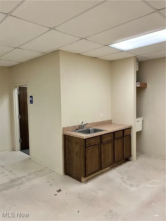 Bar featuring sink, a drop ceiling, and dark brown cabinetry