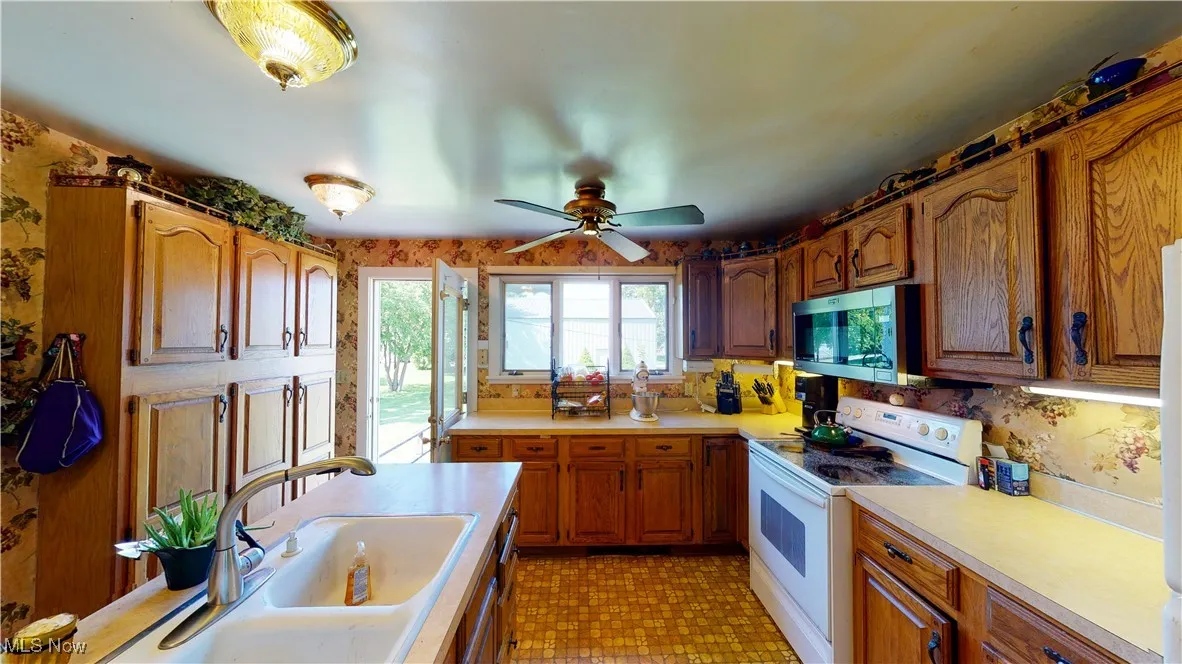 Kitchen with sink, white electric stove, and ceiling fan