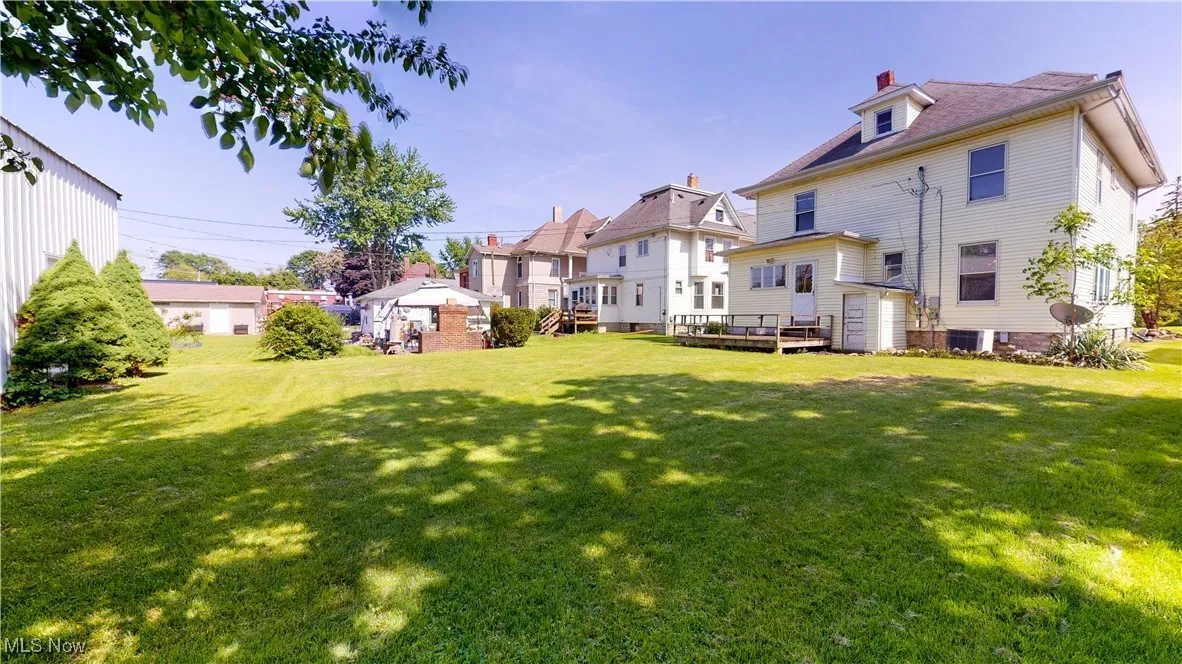 Back of property featuring a wooden deck, a lawn, and central air condition unit