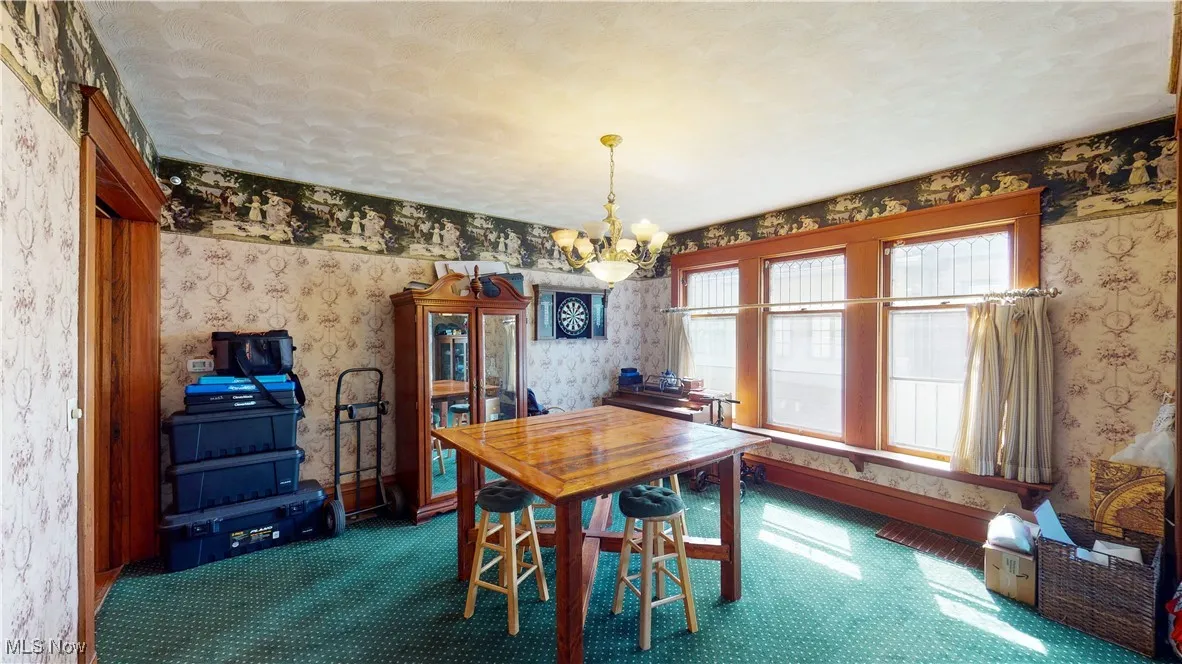 Carpeted dining area featuring a chandelier