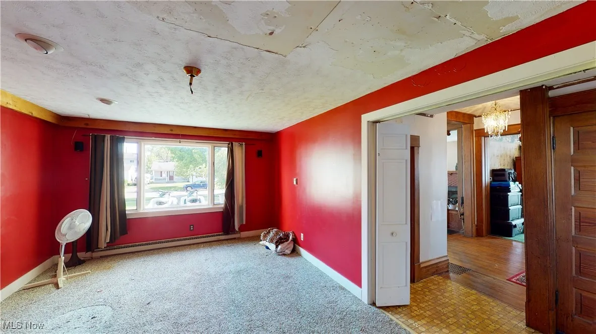 Unfurnished room with a notable chandelier, a textured ceiling, and a baseboard heating unit