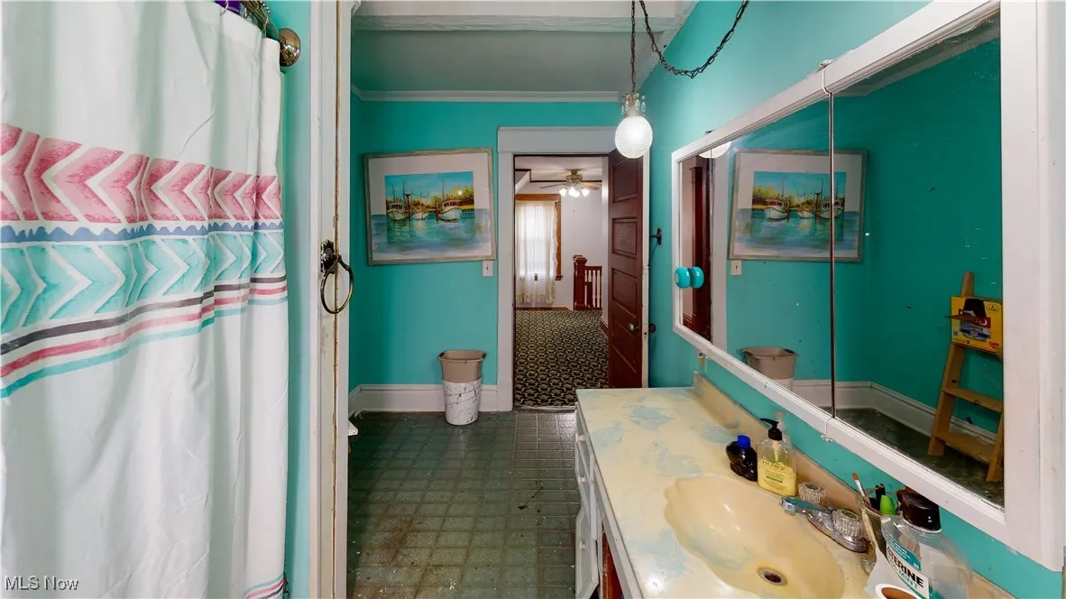 Bathroom featuring crown molding, ceiling fan, vanity, and walk in shower