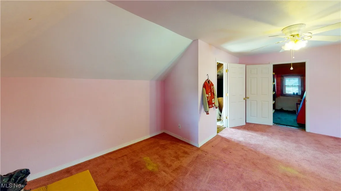 Bonus room featuring vaulted ceiling, light colored carpet, and ceiling fan