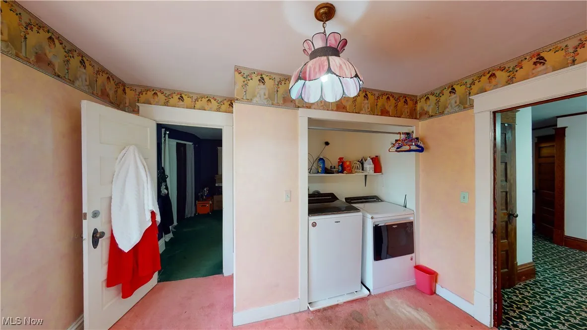 Laundry area featuring washing machine and clothes dryer and light carpet