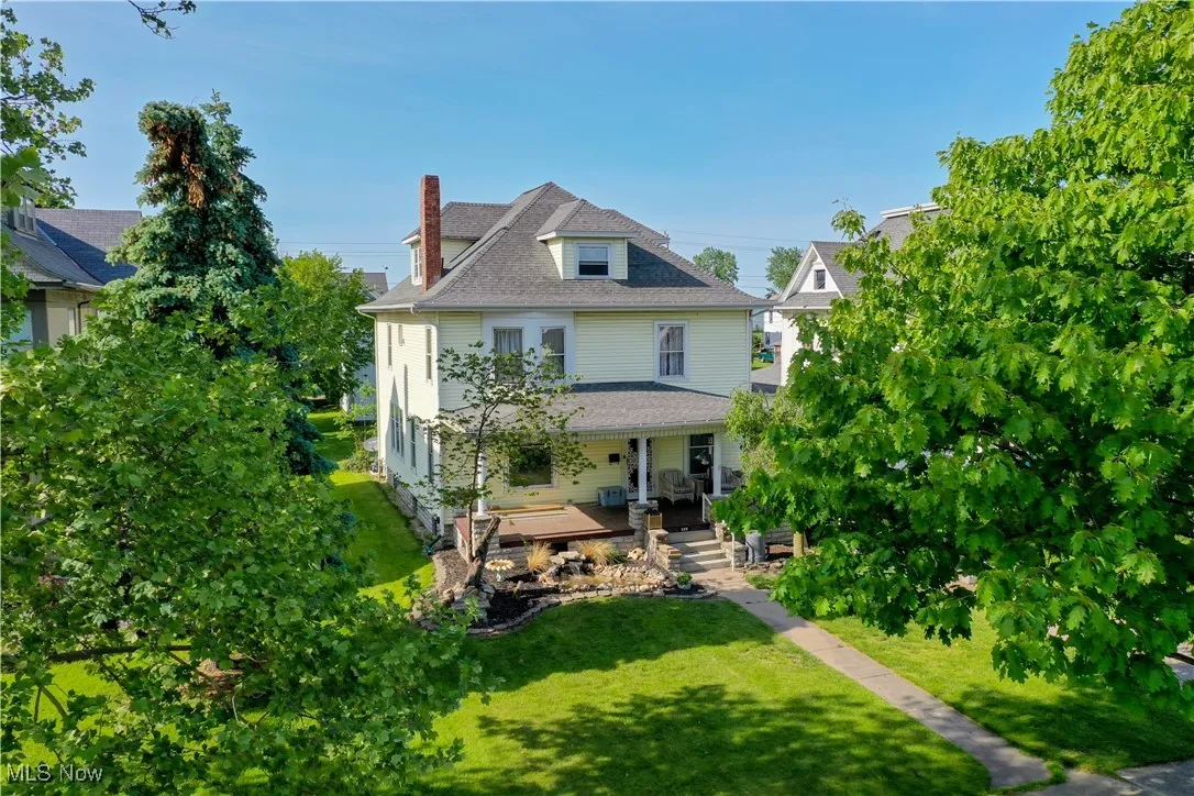 Back of house with a yard and covered porch
