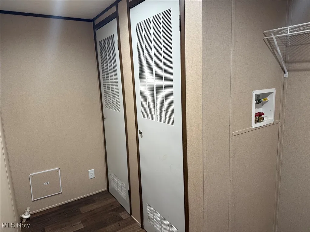 Washroom with a heating unit, hookup for a washing machine, and dark wood-type flooring