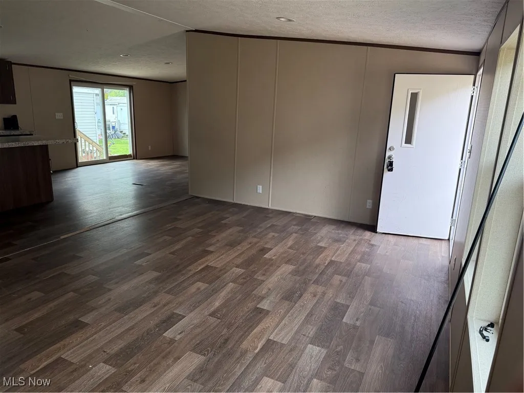 Unfurnished living room featuring dark wood finished floors and a textured ceiling