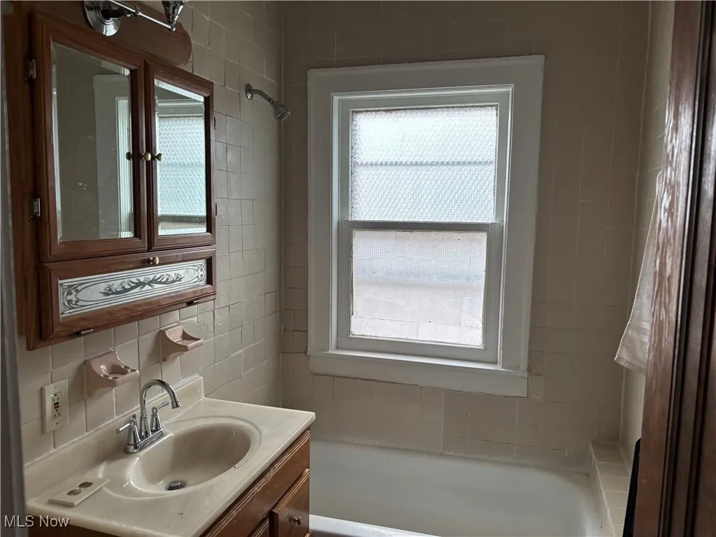 Bathroom with vanity, tile walls, and backsplash