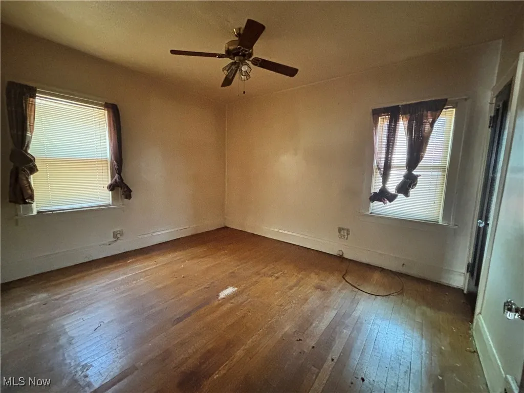 Unfurnished room featuring baseboards, a ceiling fan, and hardwood / wood-style floors