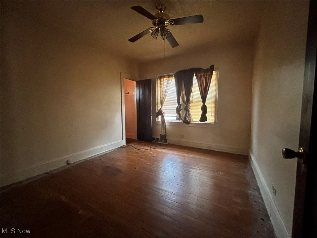 Unfurnished room featuring wood-type flooring, baseboards, and ceiling fan