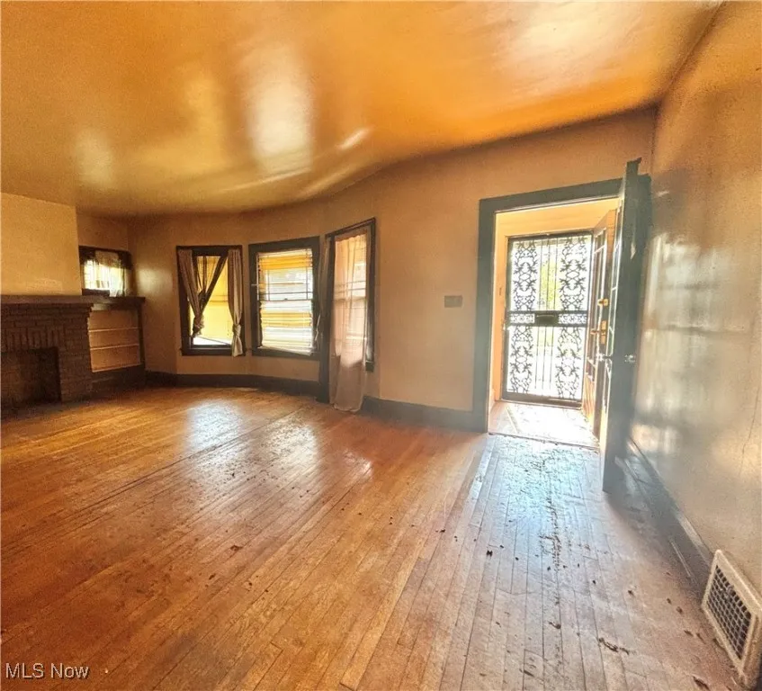 Unfurnished living room with a fireplace, wood-type flooring, and visible vents