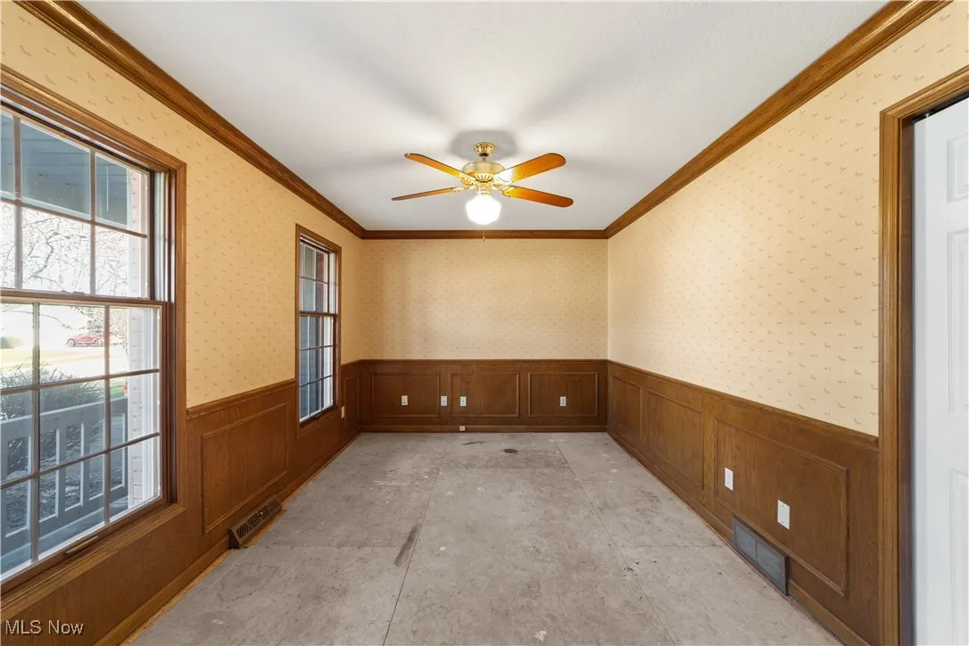 Large bedroom/library on the 1st floor with wood trim and wood paneling and a ceiling fan...Plenty of light with large windows !!!