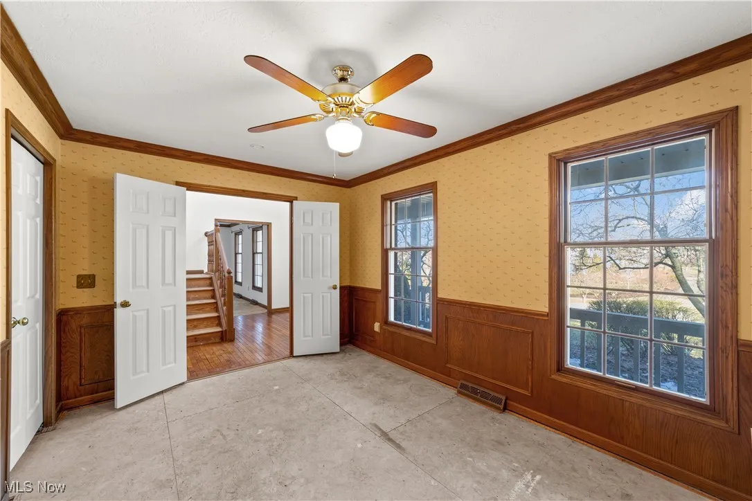 Large bedroom/library on the 1st floor with wood trim and wood paneling and a ceiling fan...Plenty of light with large windows !!!
