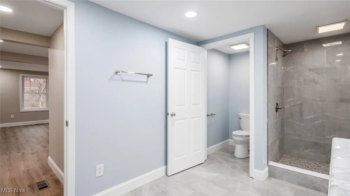 Bathroom featuring a tile shower and toilet