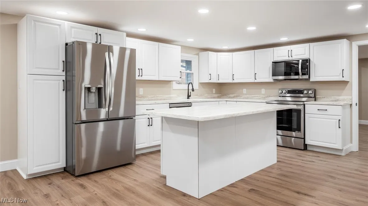 Kitchen featuring stainless steel appliances, white cabinetry, a kitchen island, and light hardwood / wood-style floors