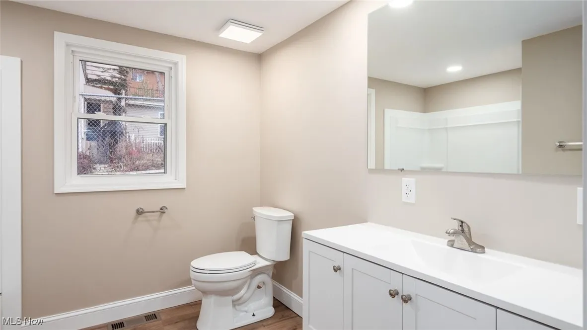 Bathroom with hardwood / wood-style flooring, vanity, and toilet