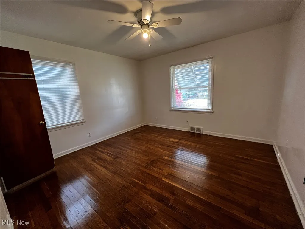 Unfurnished bedroom with dark wood-type flooring and ceiling fan