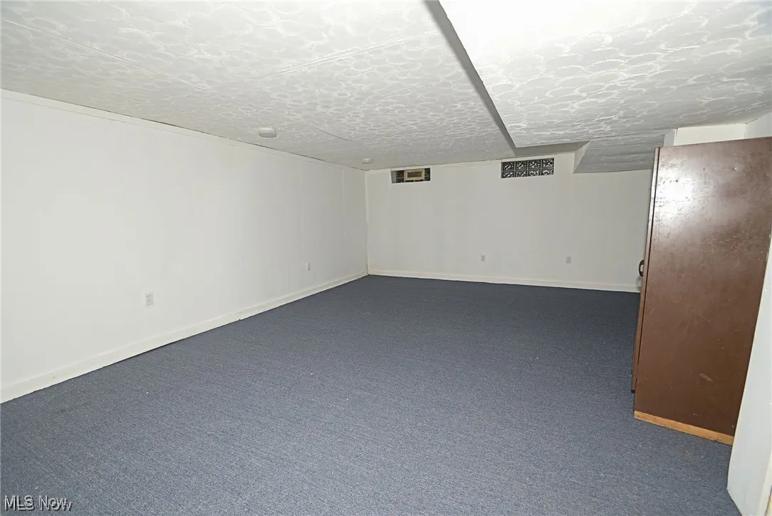Basement with carpet flooring and a textured ceiling