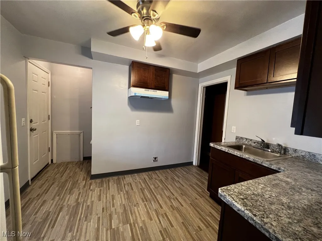 Kitchen featuring sink, dark brown cabinets, ceiling fan, and light wood-type flooring