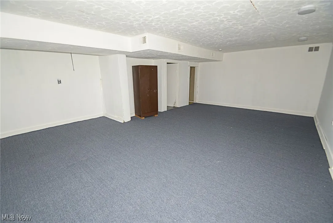 Basement featuring a textured ceiling and carpet flooring