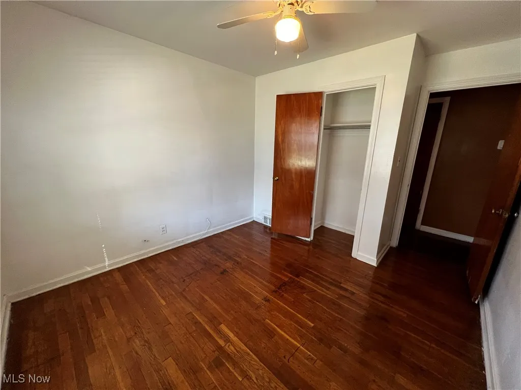 Unfurnished bedroom featuring dark hardwood / wood-style floors, ceiling fan, and a closet