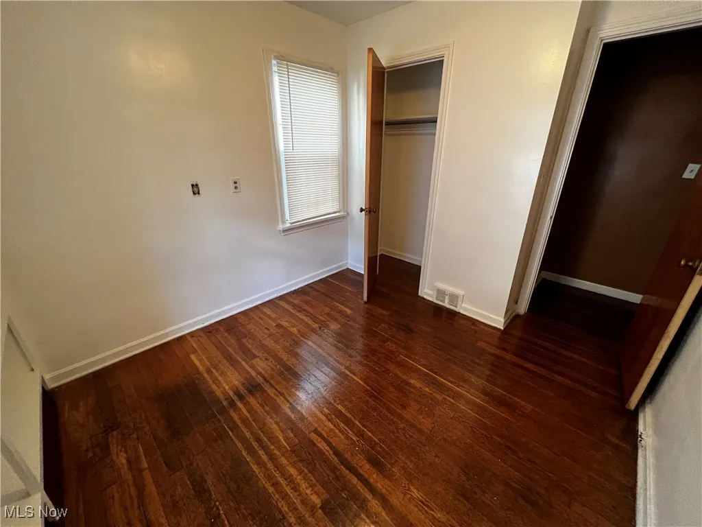 Unfurnished bedroom with dark hardwood / wood-style flooring and a closet